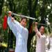 Cours de Tai chi chuan avec un sabre dans un parc.