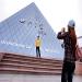 Un jeune touriste chinois se fait photographier devant la reproduction de la pyramide du Louvre dans un parc d